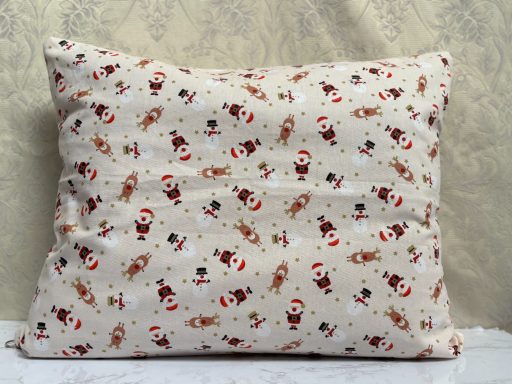 Cushion with a festive pattern featuring Santa Claus and reindeer on a cream background.