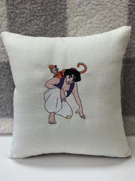A decorative cushion featuring a character crouching, with a monkey on their shoulder.