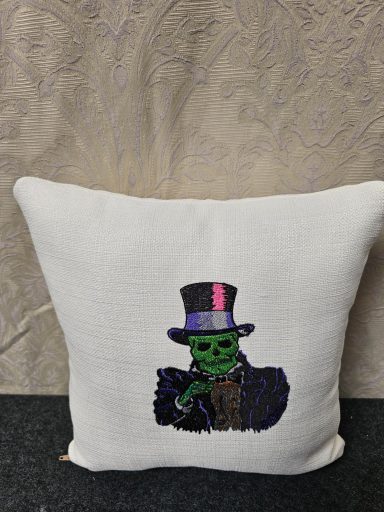 A decorative cushion featuring a green skeleton in a top hat and purple accents.