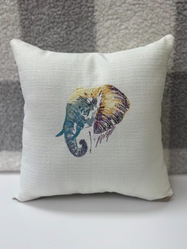 Cushion with a multicoloured elephant illustration on a textured white background.
