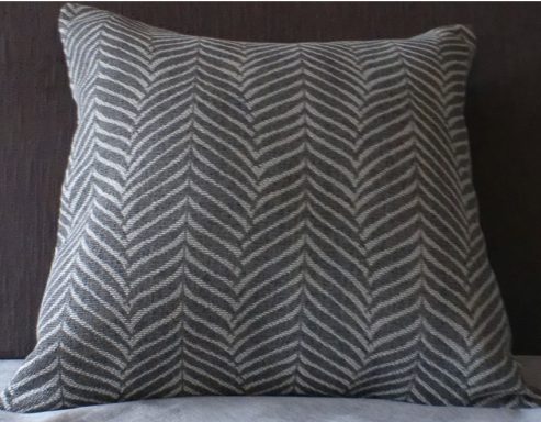 Square cushion with a chevron pattern in neutral tones.