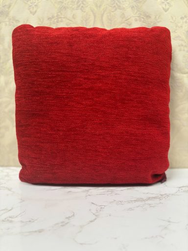 Red square cushion with a textured surface.