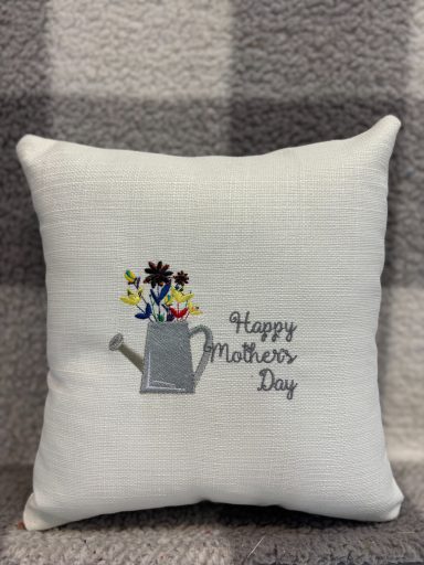 Embroidered cushion featuring a watering can and flowers with "Happy Mother's Day" text.