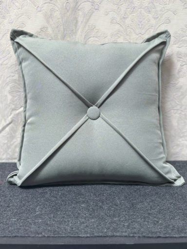 Square light green cushion with a centre button and stitched diagonal lines.