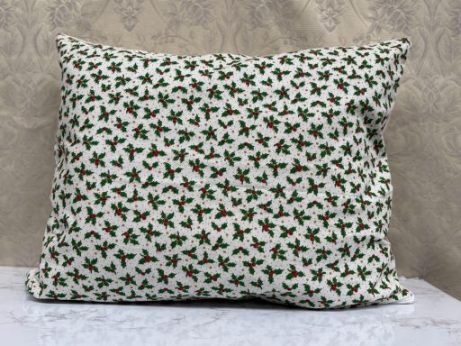 Cushion cover with a pattern of green holly leaves and red berries on a white background.