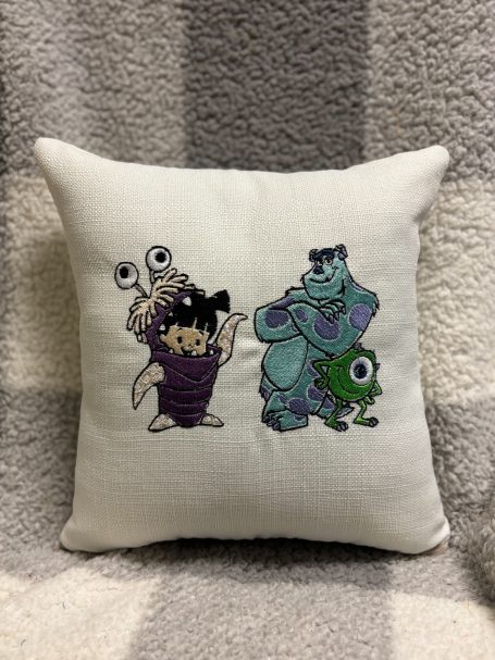 Cushion featuring cartoon characters: a purple monster, a child, and two monsters.