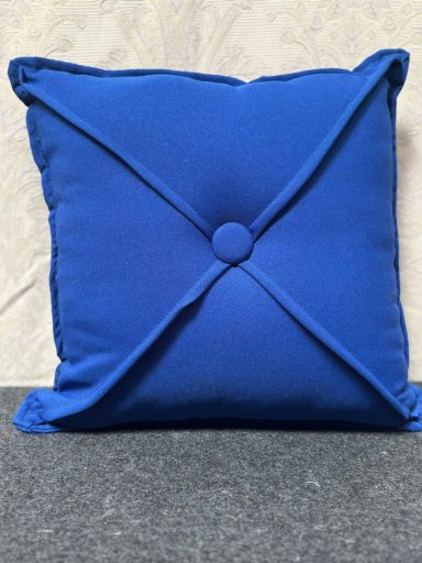 Bright blue square cushion with a button in the centre and stitched criss-cross pattern.