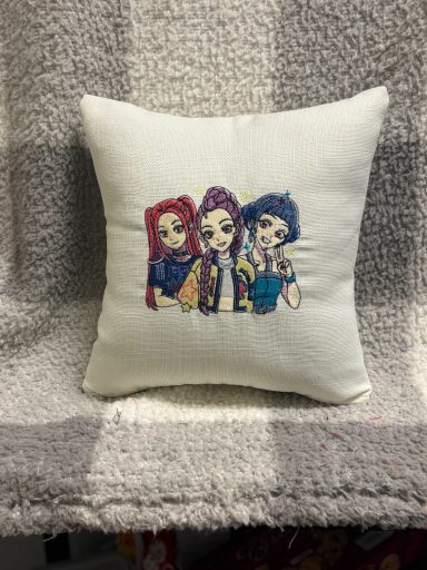 A decorative cushion featuring three animated characters with vibrant hair.