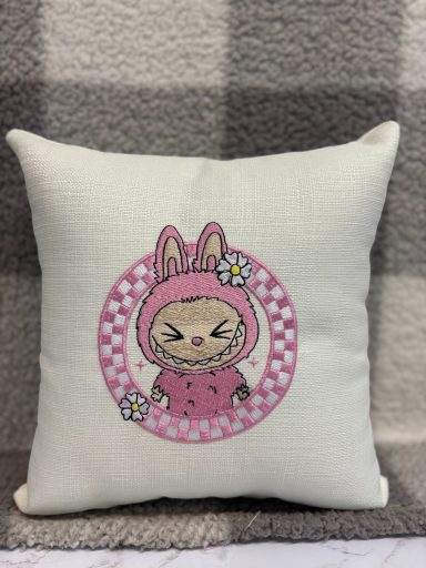 Decorative cushion featuring a cute bunny character in a pink outfit.