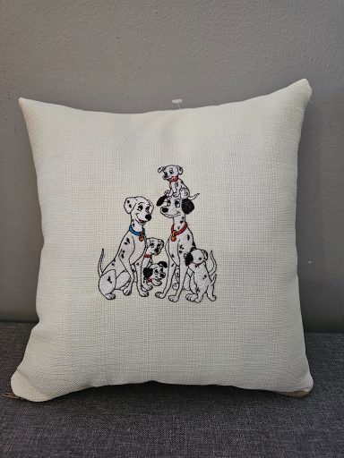 A decorative cushion featuring three Dalmatians and a smaller dog illustration.