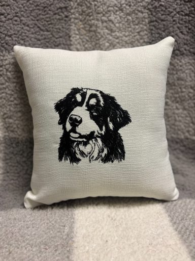Black and white illustration of a dog's face on a decorative cushion.