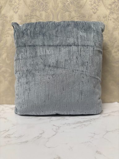 Light grey cushion on a marble surface with a textured finish.