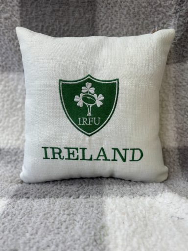 White cushion featuring a green shield with a shamrock and the word "IRELAND".