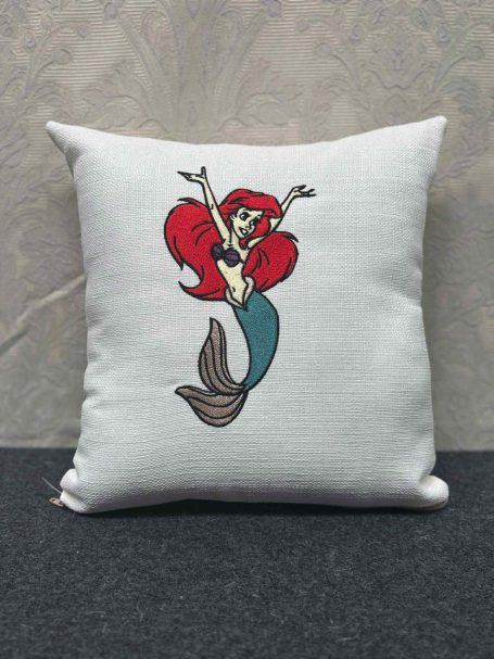 Embroidered cushion featuring Ariel, the Little Mermaid, with vibrant red hair and a teal tail.