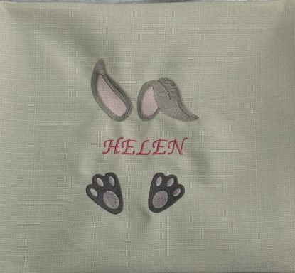 A soft cushion featuring bunny ears and paws with the name "HELEN" in pink.