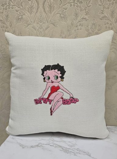 Cream cushion featuring an embroidered cartoon character in a red heart.