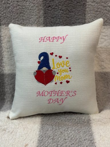 A decorative cushion with "Happy Mother's Day" and "I love you mom" in bright colours.