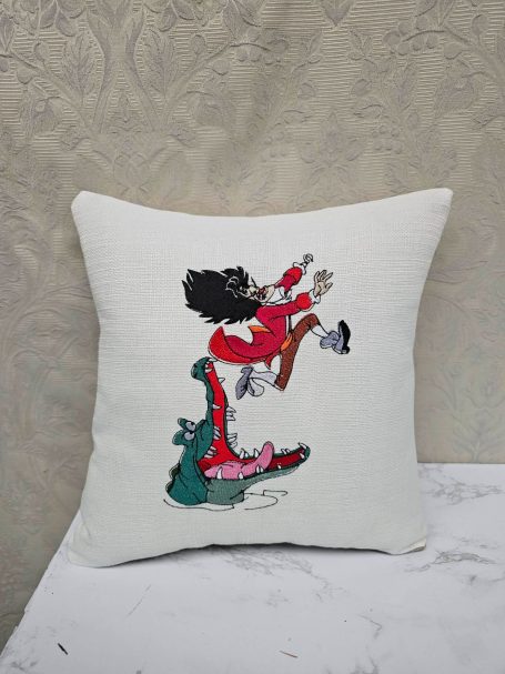 A decorative cushion featuring a character in a red outfit and a playful green creature.