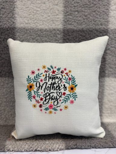Decorative cushion with "Happy Mother's Day" surrounded by floral designs.