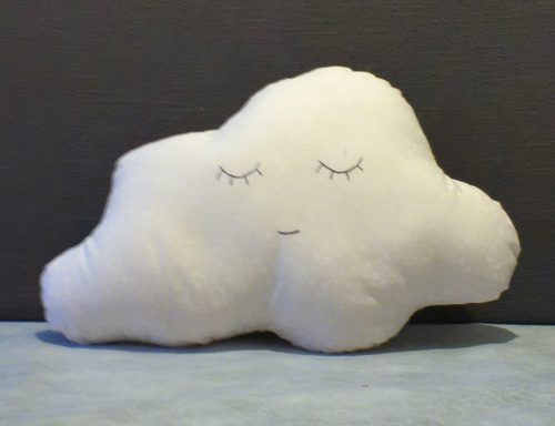 Soft, cloud-shaped pillow with a smiling face and closed eyes.