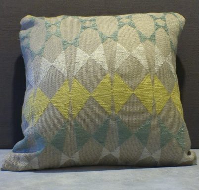 Decorative cushion with a geometric pattern in yellow, teal, and grey tones.