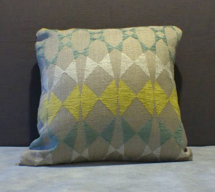Decorative cushion with a geometric pattern in beige, teal, and yellow hues.