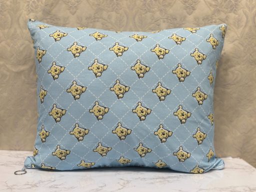 A light blue decorative pillow featuring a pattern of yellow cartoon bears.