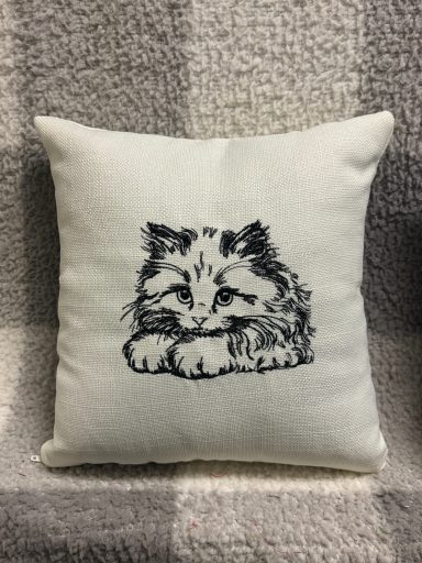 A decorative cushion featuring a sketch of a lying cat.
