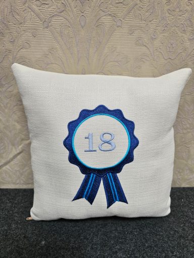 Cushion featuring a blue ribbon design with the number 18 in the centre.
