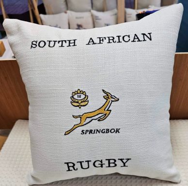 Cream cushion with "South African Rugby" text and a Springbok logo.