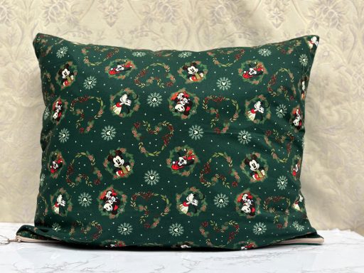 Green pillow with festive patterns featuring Mickey Mouse and Christmas motifs.