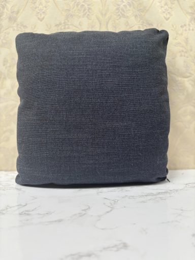 Square dark blue cushion against a light patterned background.