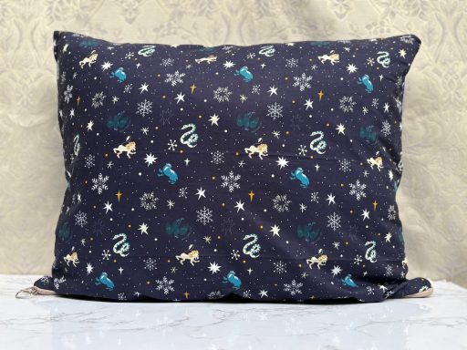 Navy pillow with a whimsical pattern of snowflakes and various winter-themed motifs.