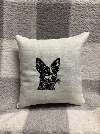 Small cushion with a black-and-white illustration of a dog’s face on a light background.