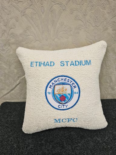 Cushion featuring "Etihad Stadium" and Manchester City logo in blue and white.