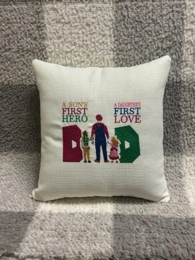 Cushion with text: "A father's first hero, a daughter's first love" alongside illustrations.