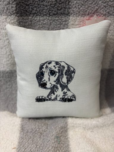 A cushion featuring an illustration of a spotted dog.