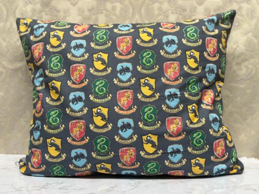 Pillow featuring a patterned design with various colourful crests on a dark background.