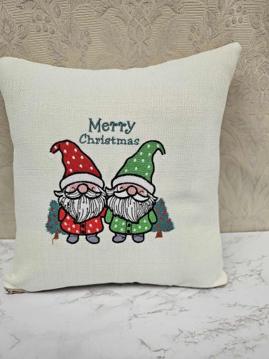 Two gnomes in Christmas hats with the text "Merry Christmas" on a cushion.