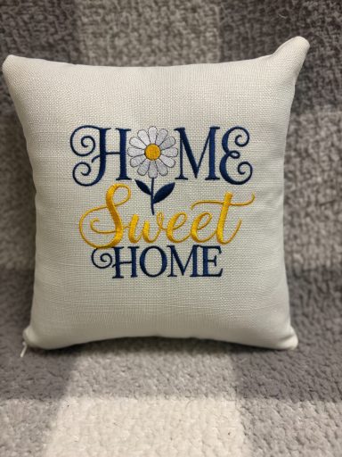 Cushion with "Home Sweet Home" text and a flower design.