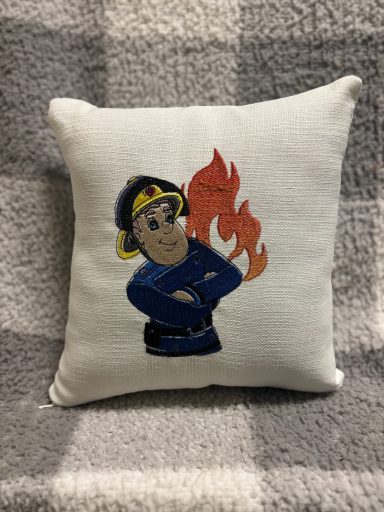 A decorative cushion featuring a cartoon firefighter with flames behind him.