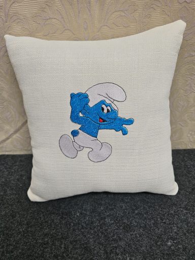 A decorative cushion with a blue Smurf cartoon character.