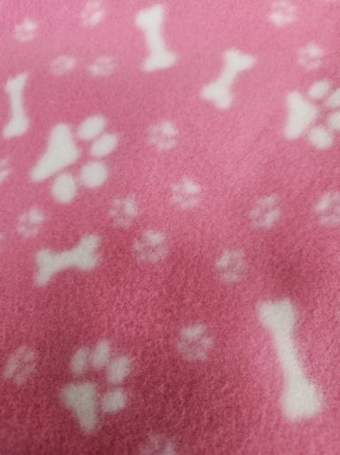 Pink fleece fabric with white paw prints and bone patterns.