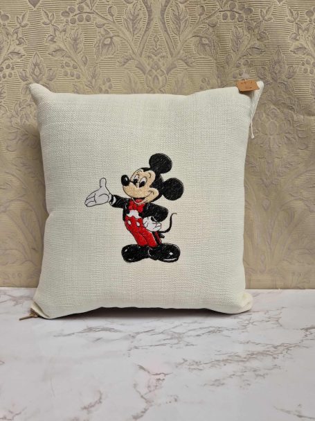 Cream cushion featuring an embroidered Mickey Mouse in red shorts.