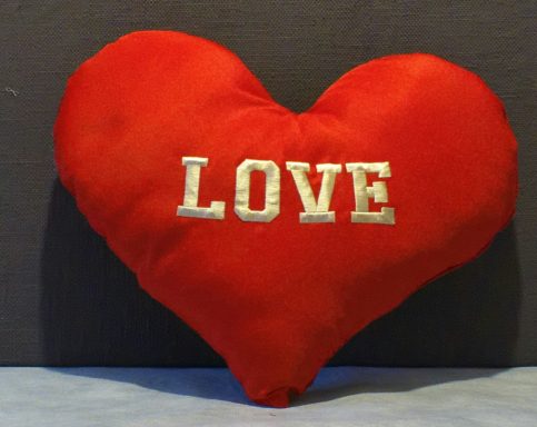 Red heart-shaped cushion with the word "LOVE" embroidered in white.