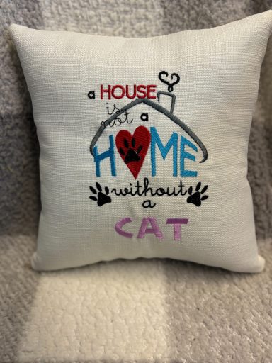 Cushion with the quote: "A house is not a home without a cat" in colourful text.