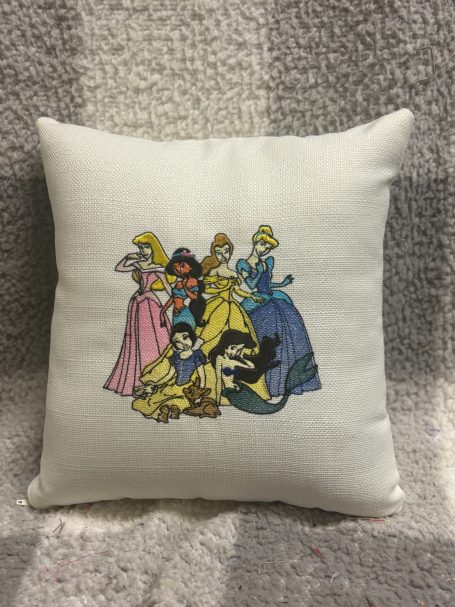 A decorative cushion featuring several princesses from animated films.