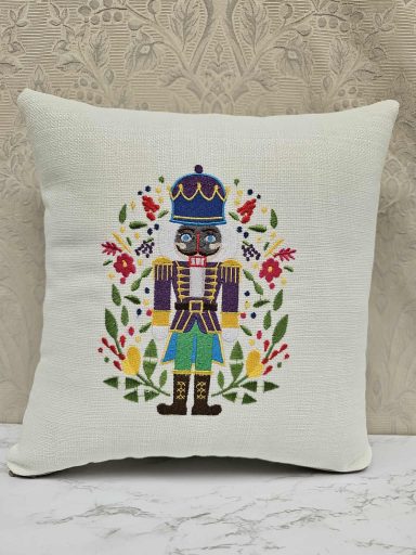 Colourful nutcracker figure surrounded by floral designs on a cushion.