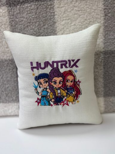 Cushion featuring cartoon characters and the name "HUNTRIX" in colourful lettering.