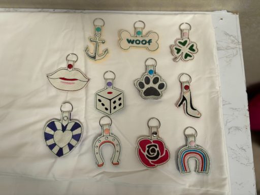 A collection of ten colourful keychains featuring various designs, including an anchor, bone, and flower.